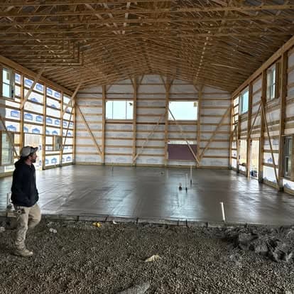 Interior view of a construction site showing framing and concrete floor preparation.