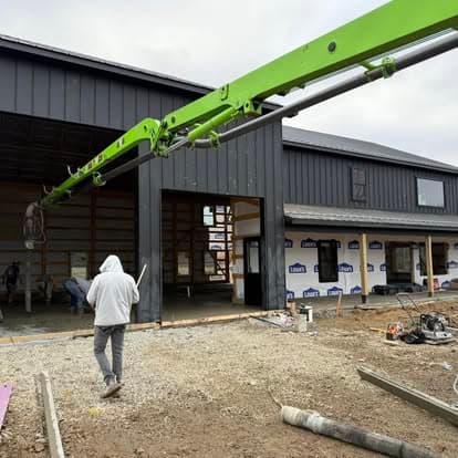 Construction site with a green crane and worker, showcasing a new building structure.