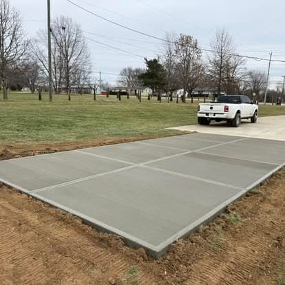 Concrete driveway installation in a grassy area with a white pickup truck nearby.