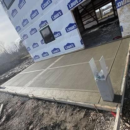 Newly poured concrete slab for construction, with Lowes branding on the surrounding walls.