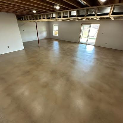 Spacious empty room with polished concrete floor and large windows for natural light.