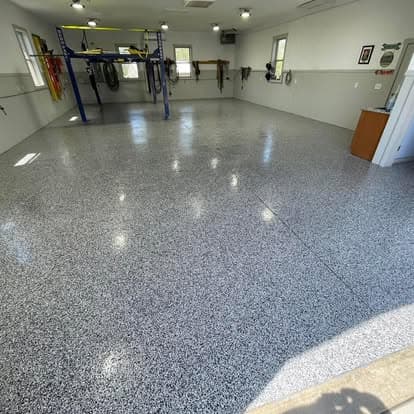 Spacious garage with epoxy flooring and equipment racks, well-lit and organized.