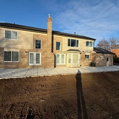 Modern two-story home with brick exterior and large windows, featuring a freshly graded yard.