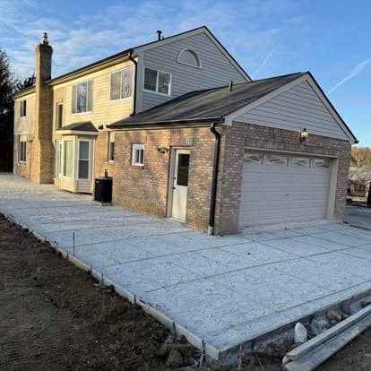 Two-story house with brick and siding, new driveway, and clear blue sky.