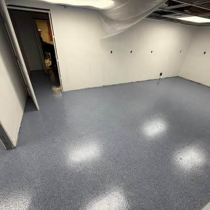 Empty room with freshly coated blue epoxy flooring and white walls, showing a clean, modern space.